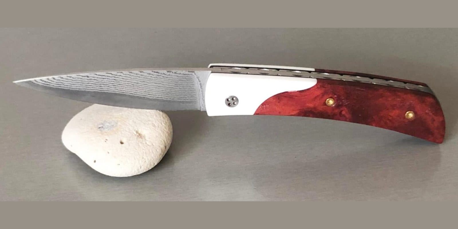 Barracuda 10 cm, Mitres en Corian, manche en Red Heart, vis or jaune 24 carats, platines guillochées, lame VG10 Suminagashi